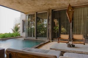 a swimming pool with two chairs and a couch at Nomade Tulum in Tulum