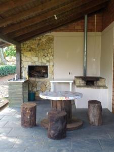 a patio with a table and logs and a stone oven at Casa de Campo Rancho Bodaneze in Abelardo Luz
