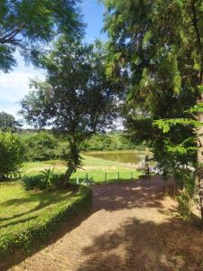 a path through a park with trees and a lake at Casa de Campo Rancho Bodaneze in Abelardo Luz