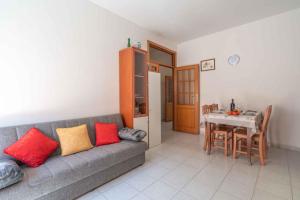 a living room with a gray couch with red and yellow pillows at Holiday home in Alghero 44952 in Alghero