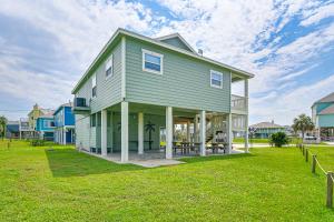 a large house on a lawn in front of some houses at Walk to Ocean Pura Vida Crystal Beach House! in Crystal Beach