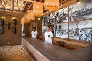 two men standing at a counter in a room with pictures on the wall at Mwezi Boutique Resort in Jambiani +37 photos