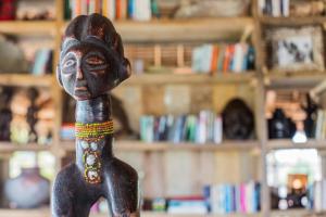 a wooden figurine of a person in front of a shelf at Mwezi Boutique Resort in Jambiani