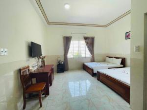 a bedroom with two beds and a desk and a tv at Magnolia Hotel Cam Ranh in Cam Ranh