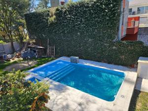 a swimming pool in a yard next to a hedge at Casa Confite Baigorria in Paganini