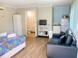 a bedroom with a bed and a couch and a tv at Riverview Tourist Park in Margaret River Town