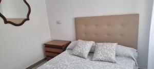 ein Schlafzimmer mit einem Bett mit zwei Kissen und einem Spiegel in der Unterkunft Habitación Matrimonio cerca a la Playa de Poniente in Benidorm