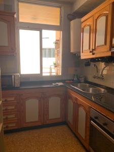a kitchen with wooden cabinets and a sink and a window at Apartamento maspalomas 3 hab stay in gran canaria in Maspalomas