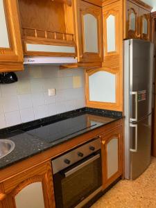 a kitchen with wooden cabinets and a stainless steel refrigerator at Apartamento maspalomas 3 hab stay in gran canaria in Maspalomas +21 photos