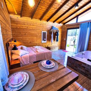 a bedroom with a bed and a tub and a table at Cabanas Colina Do Sol in Cambará