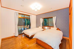 two beds in a room with two windows at JoYSOUNDカラオケBBQや麻雀セット完備断崖の上に建てられた大型貸別荘 in Tsumagoi