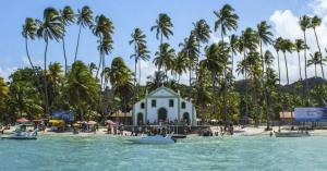 a white building on a beach with palm trees at Carneiros Paradise - Casa de Luxo em Condomínio in Tamandaré