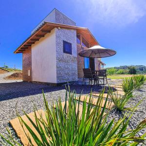 a small house with a table and an umbrella at Cabanas Colina Do Sol in Cambará