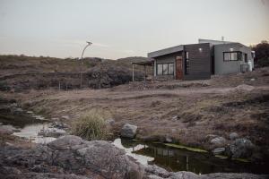 una casa sentada en la cima de una colina junto a un río en Cabaña en Tala Cruz a 9km de Villa Cañada del Sauce, en Tala Cruz