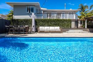 a swimming pool in front of a house at Aloha Cottage with Pool & Spa, Waiheke in Oneroa
