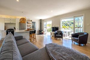a living room with a couch and chairs and a kitchen at Aloha Cottage with Pool & Spa, Waiheke in Oneroa