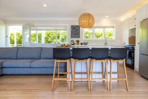a kitchen and living room with a blue couch at Aloha Cottage with Pool & Spa, Waiheke in Oneroa