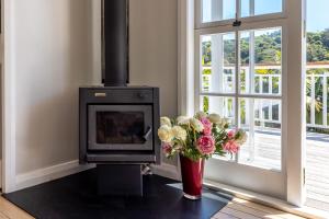 a fireplace with a vase of flowers next to a window at Aloha Cottage with Pool & Spa, Waiheke in Oneroa +17 photos