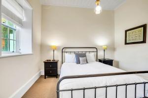 una camera bianca con un letto e due lampade di Cottage on James circa 1855 a Port Fairy