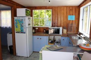 une cuisine avec des armoires bleues et un réfrigérateur blanc dans l'établissement OCEANSIDE - Exclusive & private - Castaway Cottage, à Tuateawa