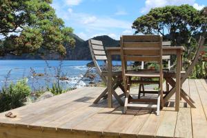 deux chaises et une table posées sur un quai en bois dans l'établissement OCEANSIDE - Exclusive & private - Castaway Cottage, à Tuateawa 13 autres photos