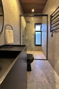 a bathroom with a toilet and a glass shower at Dolce Vista Hospedagem in Garibaldi