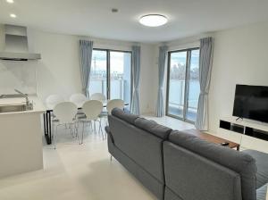 un salon avec un canapé et une table avec des chaises dans l'établissement Kairyu Marine park Guest house 海竜マリンパークゲストハウス #HH9, à Horioka