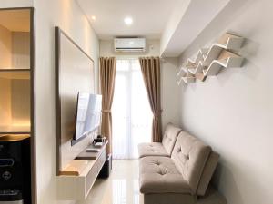a living room with a couch and a television at Comfort Stay 1BR at Vasanta Innopark Apartment By Travelio in Cikarang