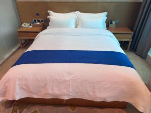 a large bed with a blue and white comforter at 海岸秀月楼酒店 in Shenzhen +4 photos