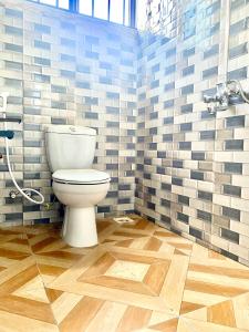 a bathroom with a toilet and a wooden floor at Sweet Family & Friendly home in Kunduchi in Dar es Salaam +14 photos