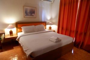 a bedroom with a large white bed with two lamps at Sanghyang Indah Spa Resort in Anyer