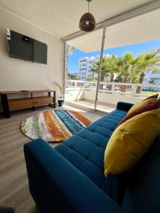 a living room with a blue couch and a large window at Cómodo departamento a pasos de la playa in La Serena +16 photos