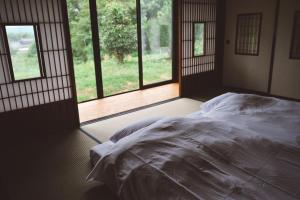ein Bett in einem Zimmer mit einem großen Fenster in der Unterkunft ëighten Private Guesthouse Yoga Retreat 一棟貸切古民家宿エイテン in Hokuto