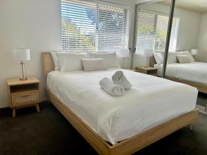 a bedroom with a large white bed with towels on it at Camelot Unit 12 in Forster