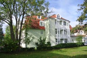 ein großes weißes Haus mit rotem Dach in der Unterkunft Fewo Rosenhof 04 in Kühlungsborn