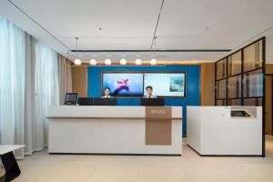 a lobby with two people sitting at a reception desk at Echarm Hotel Guangzhou East Railway Station South China Normal University Metro Station in Guangzhou
