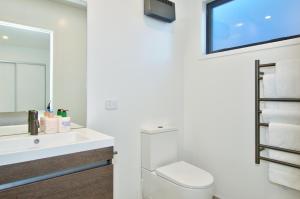 a bathroom with a toilet and a sink and a mirror at Cosy, Modern Hanley's Farm Unit - Explore Queenstown in Frankton Wharf +4 photos