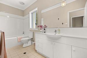 une salle de bain blanche avec toilettes et lavabo dans l'établissement Husky Haven by Experience Jervis Bay, à Huskisson