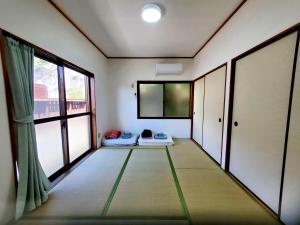an empty room with a large window and a room with at 一棟貸し みじょら しーばなコテージ in Akagina