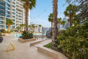 a swimming pool with palm trees and a building at Livin' Holidays - Luxury studio with Bay view in Dubai