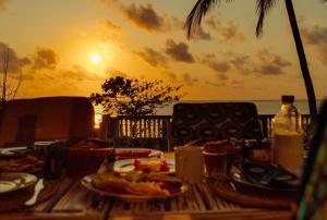 a table with food on the beach with the sunset at Villa Jasmine - Ocean Front in Bwejuu