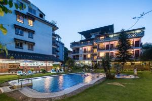 a hotel with a swimming pool in front of a building at Snow Lion Riverside Resort in Yangshuo