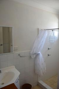 a white bathroom with a sink and a mirror at Seaspray no 5 - Bring your own linen. in South West Rocks +2 photos