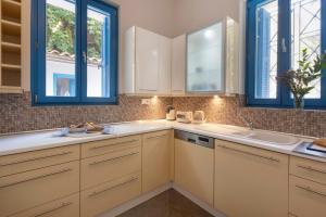 a kitchen with white cabinets and blue windows at Villa Plaka 3BR 9ppl PrivateYard 200m Metro&Museum in Athens +39 photos