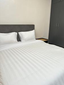 Cama grande con sábanas blancas y cabecero gris en LivLux Apartments 4, en Kampala 20 fotos más