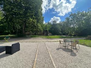 a patio with a table and chairs in a park at Gite du Tilleul - Le Petit Bois Martin in Feings