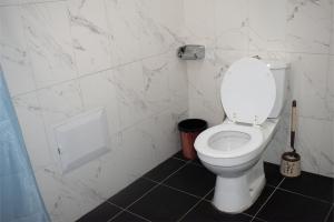 a bathroom with a white toilet and a black floor at Appartement Prestige Avec Balcon in Pointe-Noire