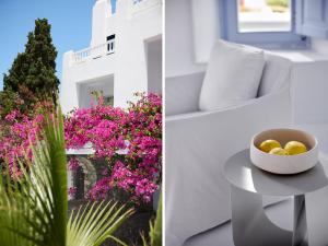 a white room with flowers and a bowl of fruit on a table at Mykonos Blu, A Grecotel Resort to Live in Psarou