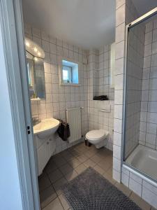 a bathroom with a sink and a toilet and a tub at Pension Stral-Sund UG in Stralsund