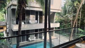 a house with a swimming pool and palm trees at Waves By Jumbo Holidayz in Alibag